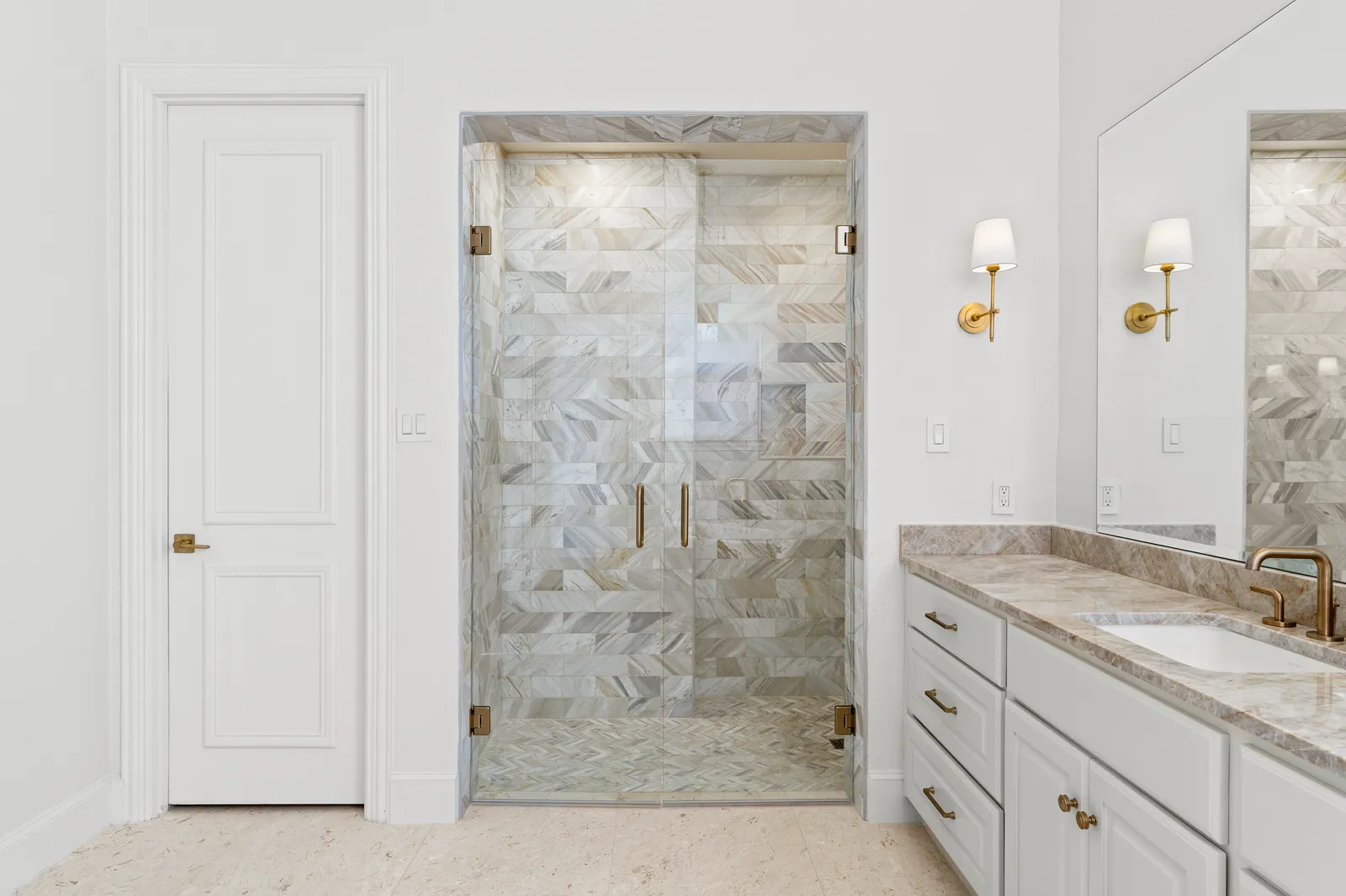 Primary bathroom at Prestwick Ln in Dallas: glass shower with marble-look tile, brass hardware, and a painted vanity