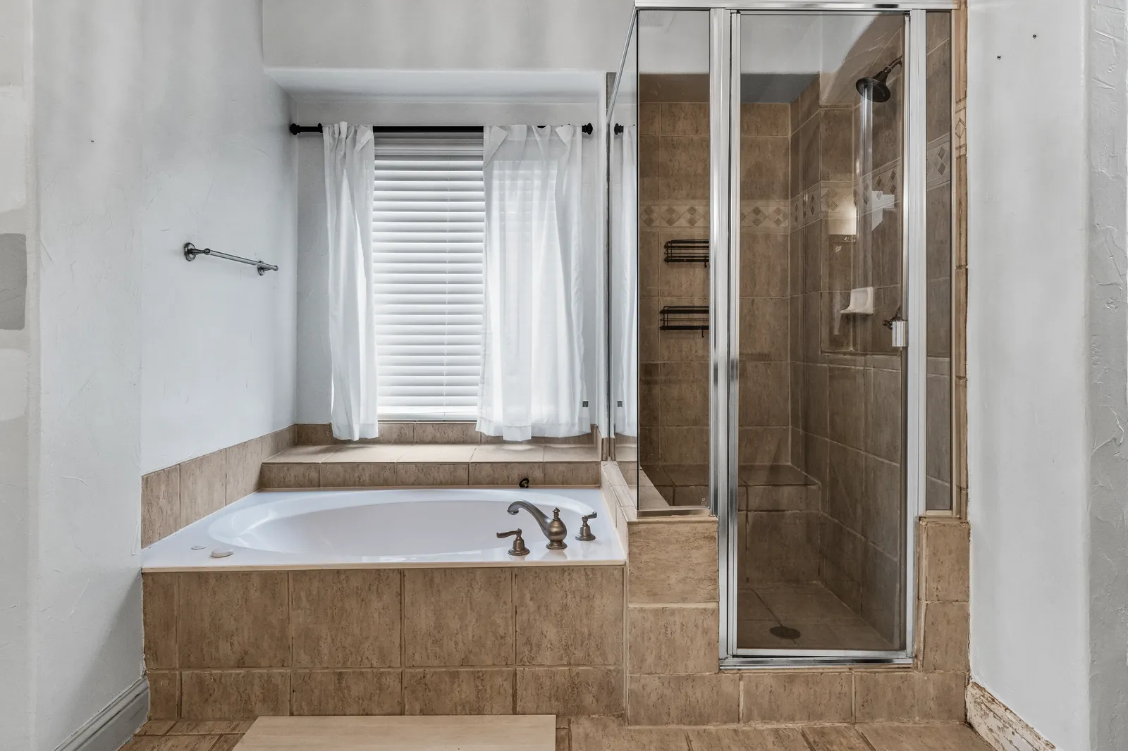 Shady Point Dr primary bathroom in Plano before the remodel: garden tub under the window and a framed shower stall