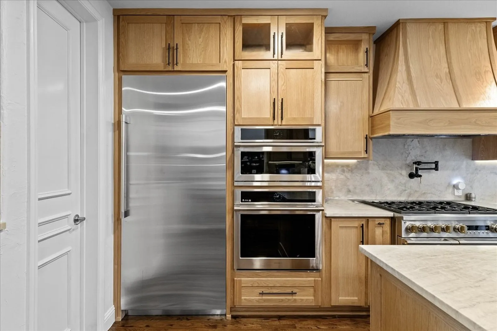 Paneled refrigerator, double ovens, and white oak cabinetry at Shady Point Dr in Plano after the remodel