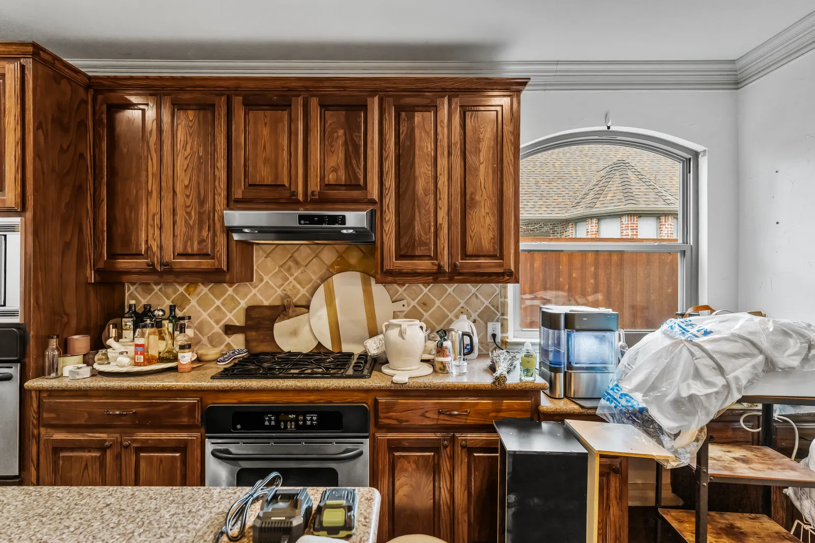 Shady Point Dr kitchen in Plano before the remodel: dark cherry cabinets, tile backsplash, and the old range under a vent hood