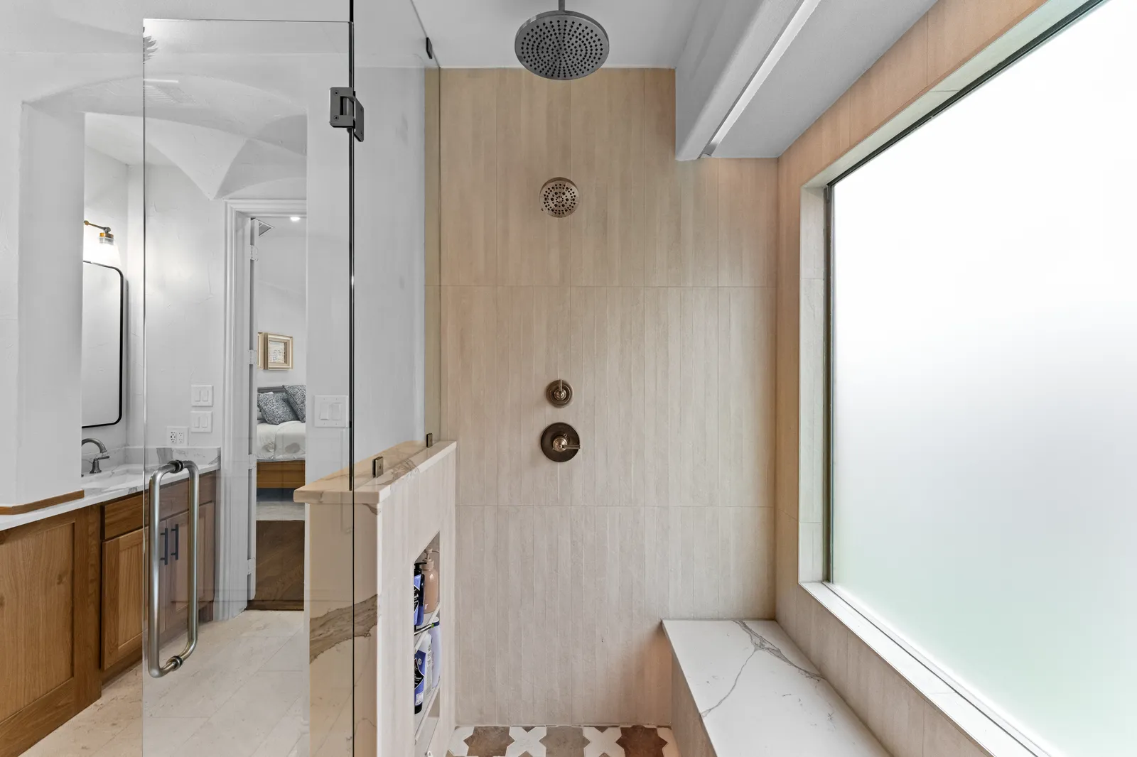 Inside the walk-in shower at Shady Point Dr in Plano: dual rain heads, a window, and a built-in bench