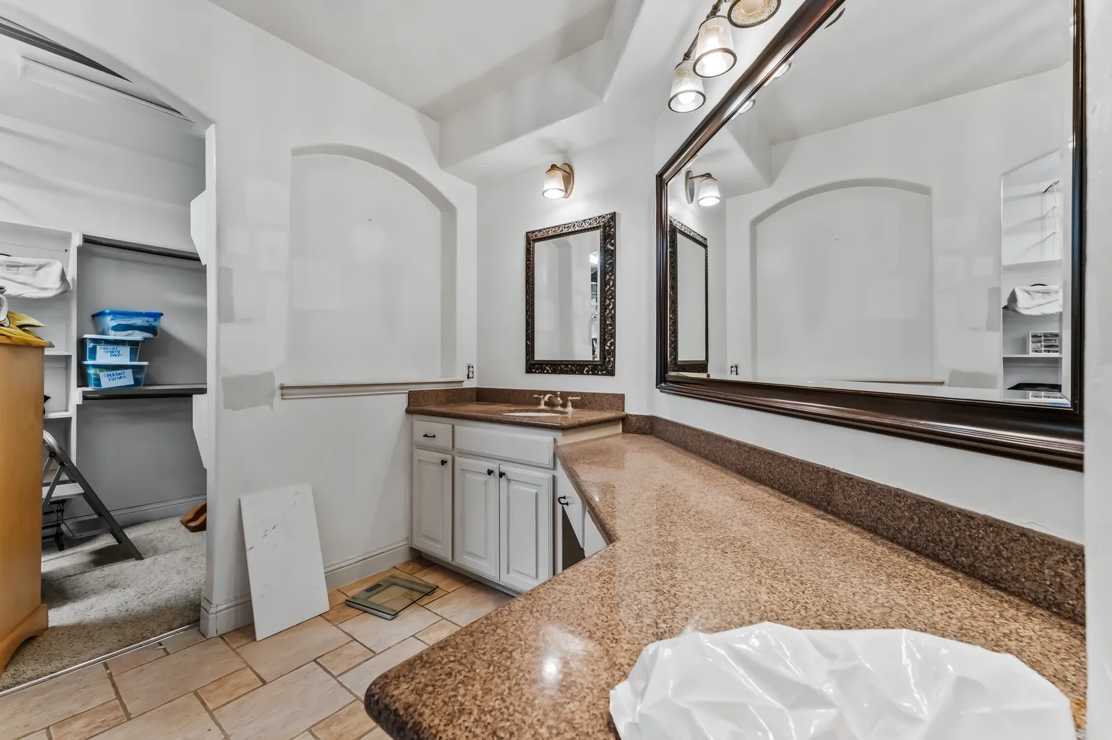 Shady Point Dr primary bathroom vanity in Plano before the remodel: brown granite counter, small white vanity, and a framed mirror