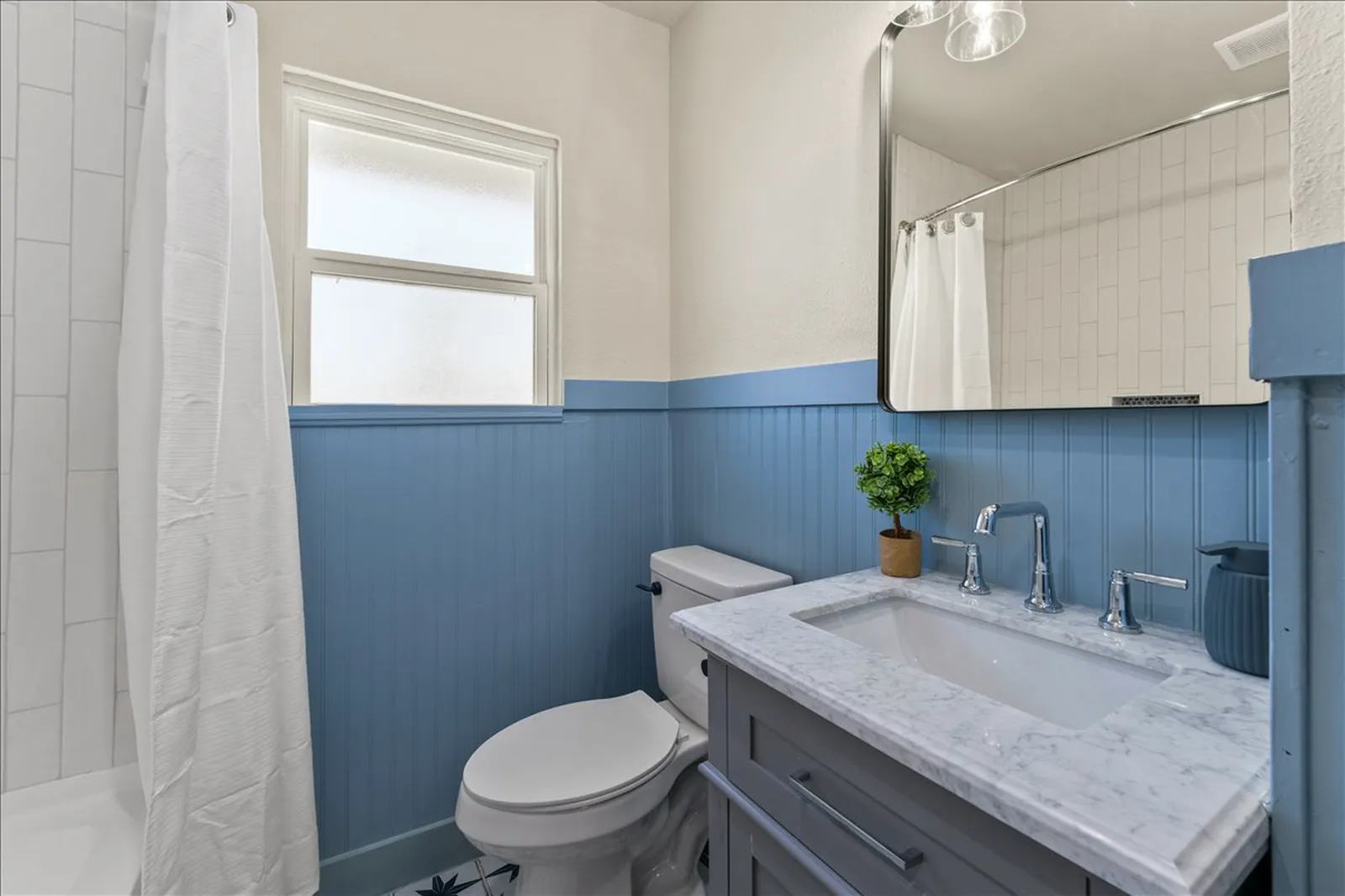 Guest bath with blue beadboard, patterned tile floor, and a new vanity at Sherman St. in Melissa