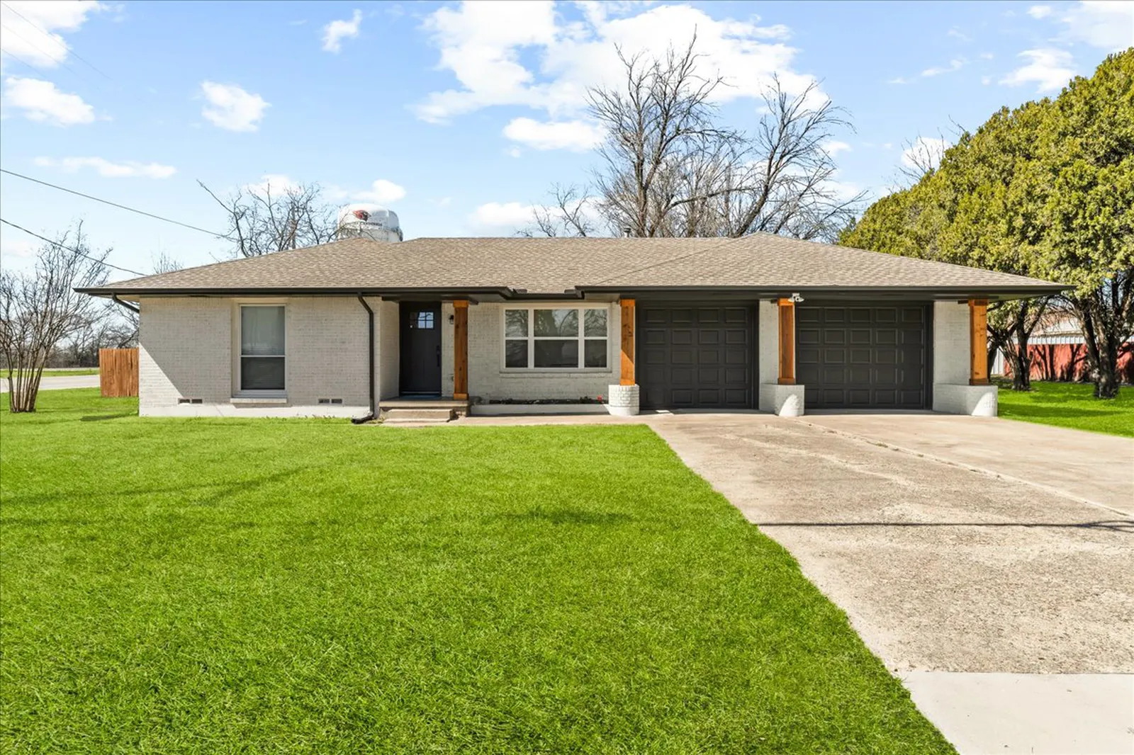 Sherman St. in Melissa after the renovation: painted brick ranch with a fresh lawn and a new front door