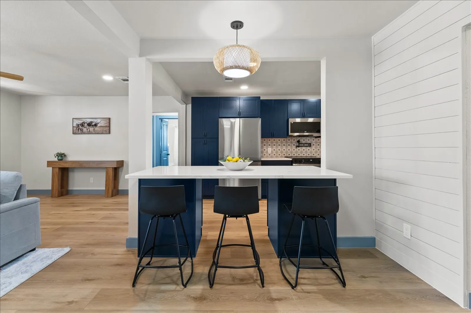 Kitchen island with seating and a rattan pendant at Sherman St. in Melissa
