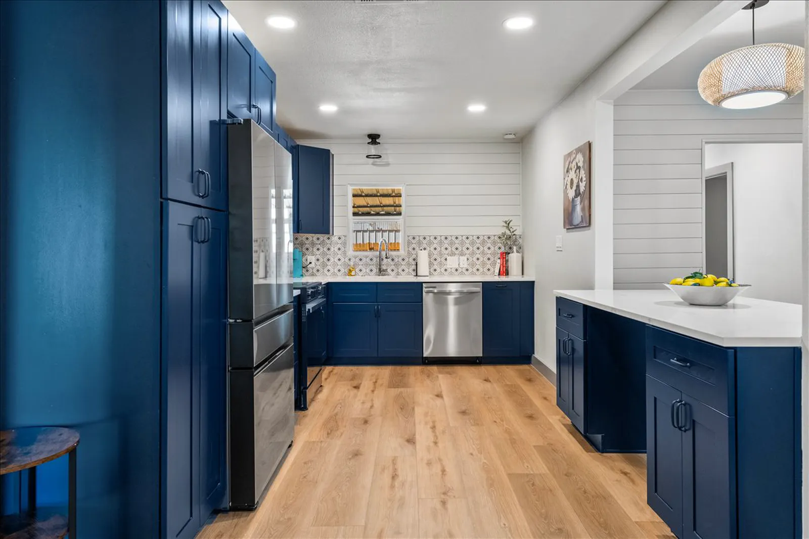 Navy kitchen with white quartz counters, patterned tile backsplash, white shiplap, and white oak floors at Sherman St. in Melissa