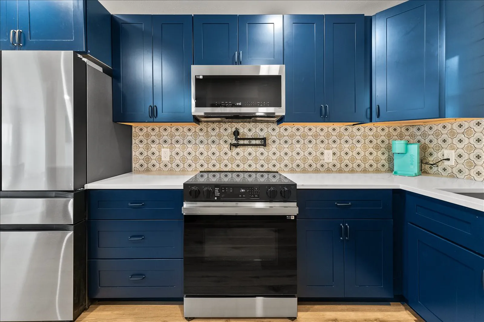 Navy cabinets, stainless range, and patterned backsplash at Sherman St. in Melissa