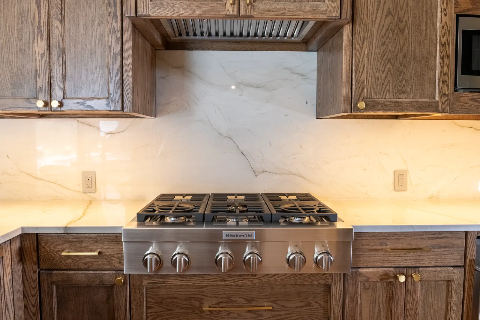 Range wall with quartzite backsplash and oak cabinetry at Vancouver Dr. in Preston Hollow
